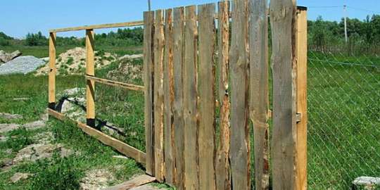 Деревянный сплошной забор из необрезной доски: правильная установка и уход за ним
